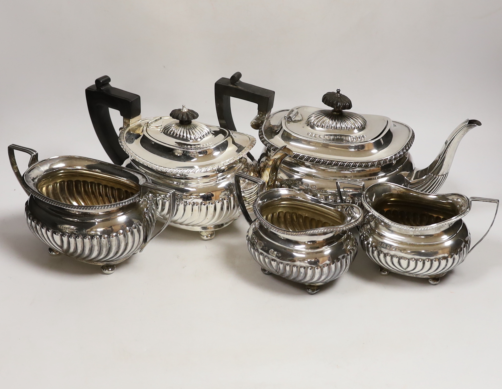 A late Victorian demi fluted silver three piece tea set, William M. Hayes, Birmingham, 1897, together with another demi fluted silver teapot and sugar bowl, same maker, Birmingham, 1898, gross weight 52.6oz.